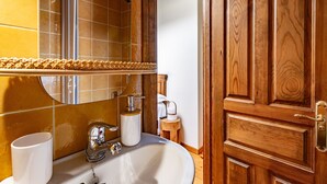 A bathroom with a sink, mirror, and wooden door. - Casa Rural Selmo in the Heart of Asturias (Zancornio)