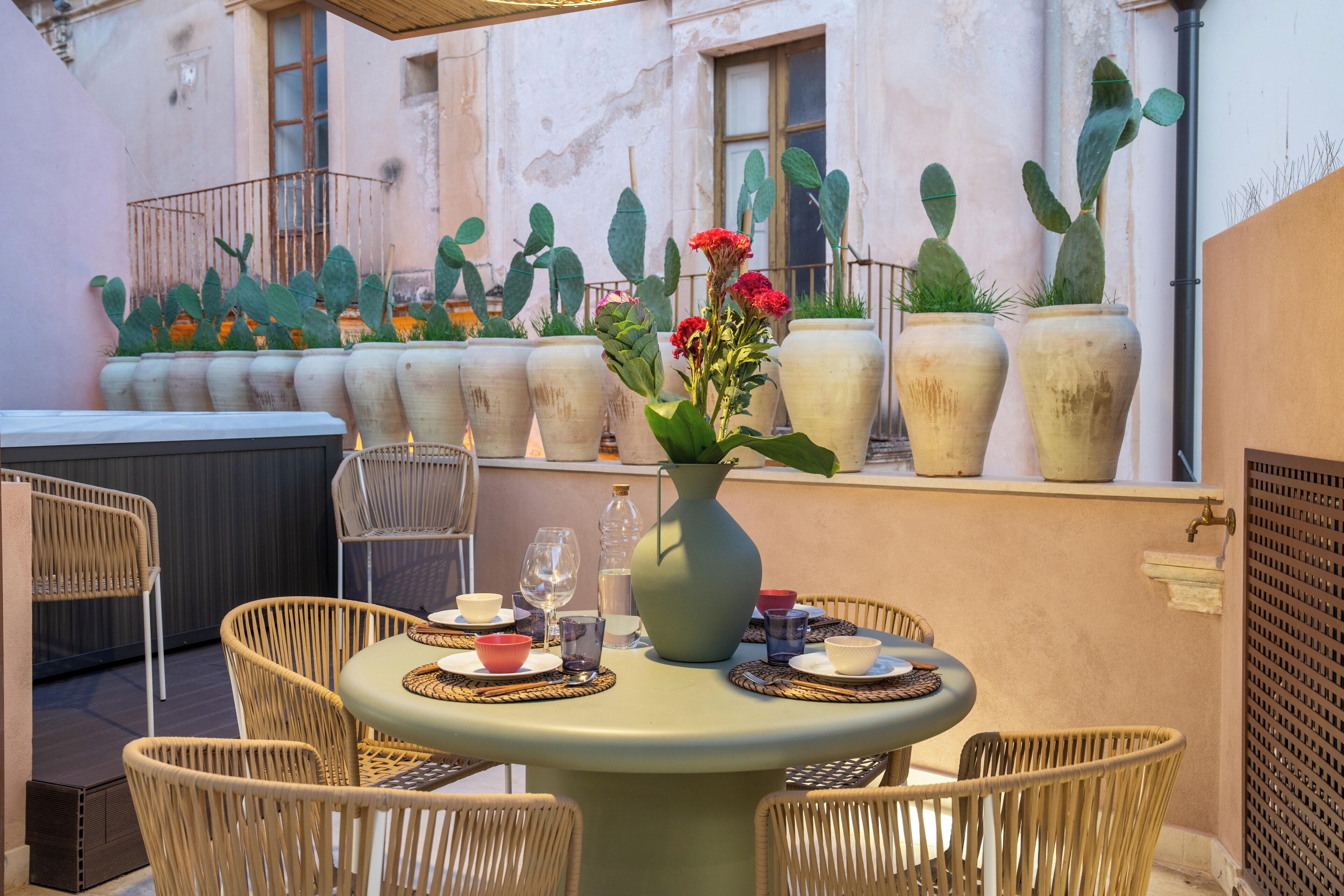 An outdoor patio with wicker chairs, a round table, and potted cacti.
