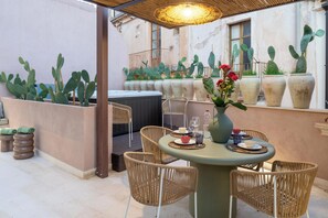 Un patio con una mesa redonda, sillas de mimbre y cactus en macetas.