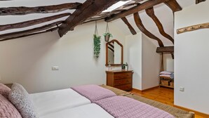 A bedroom with a bed, a dresser, a mirror, and a hanging plant.