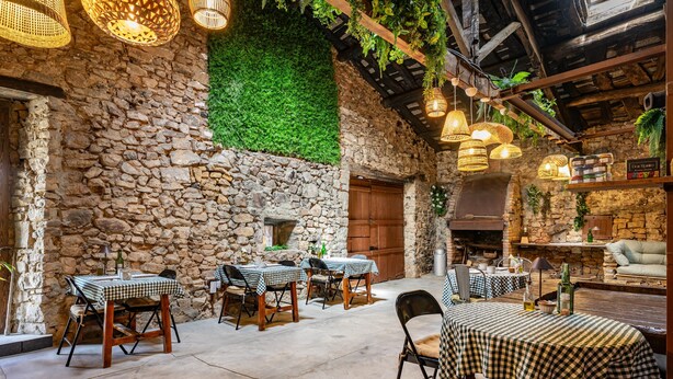A rustic outdoor dining area with stone walls, checkered tablecloths, and hanging wicker lamps. - Casa Rural Selmo in the Heart of Asturias (Zancornio)