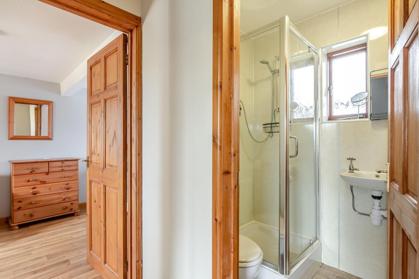 A bathroom with a glass shower enclosure, a toilet, and a sink.
