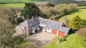 Une maison en pierre avec un toit en pente, un garage et une allée pavée.