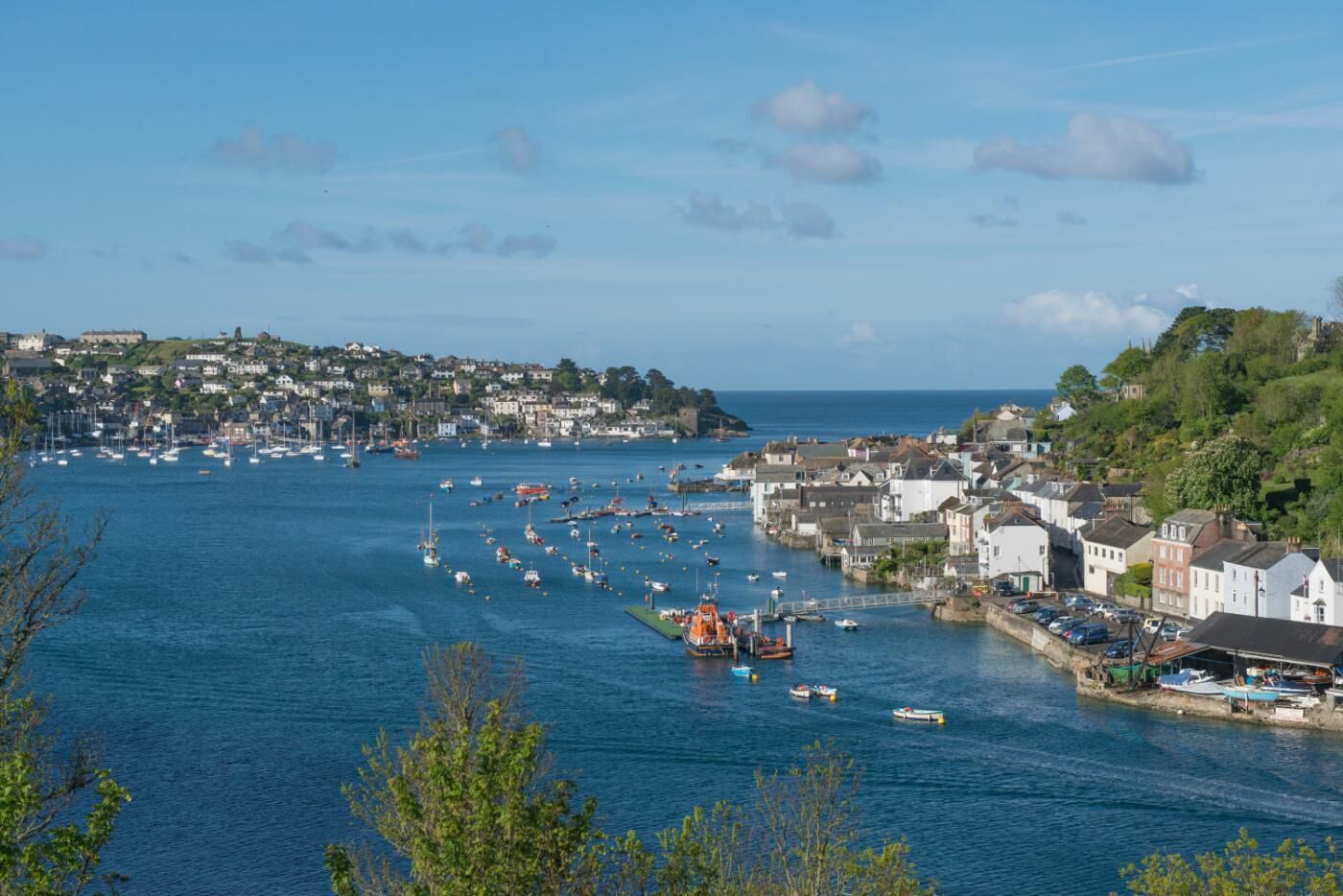 A coastal town with a harbor filled with boats, houses along the waterfront, and a bridge connecting the areas.