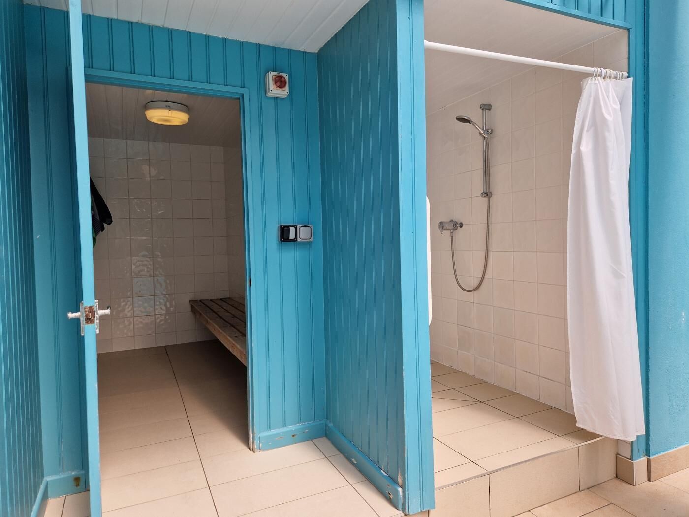 Un bagno con doccia, una panca e il water.
