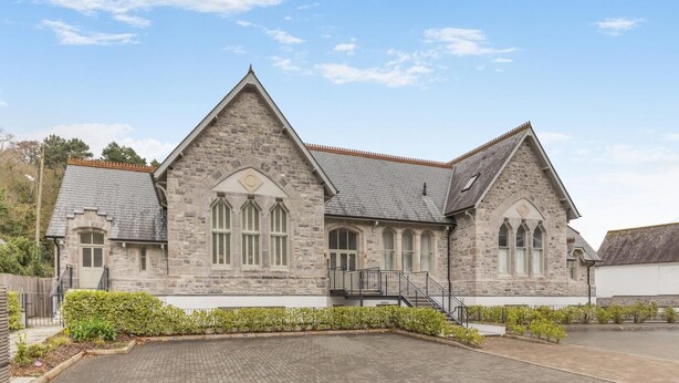 A stone building with a triangular roof, large arched windows, and a paved driveway. - 2 Bed in Fowey (oc-n33435) (Fowey)
