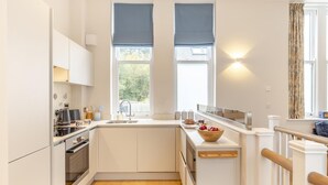A compact kitchen with white cabinetry, a double sink, and a wooden countertop. - 2 Bed in Fowey (oc-n33435) (Fowey)