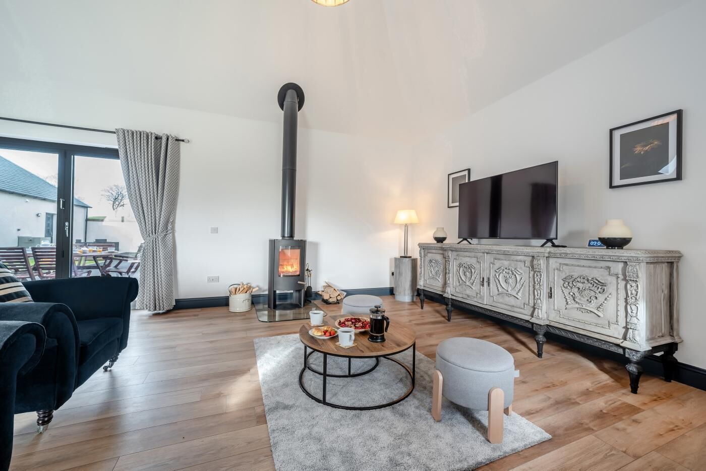 Una sala de estar con chimenea de leña, un sofá, una mesa de centro y un televisor sobre un mueble.