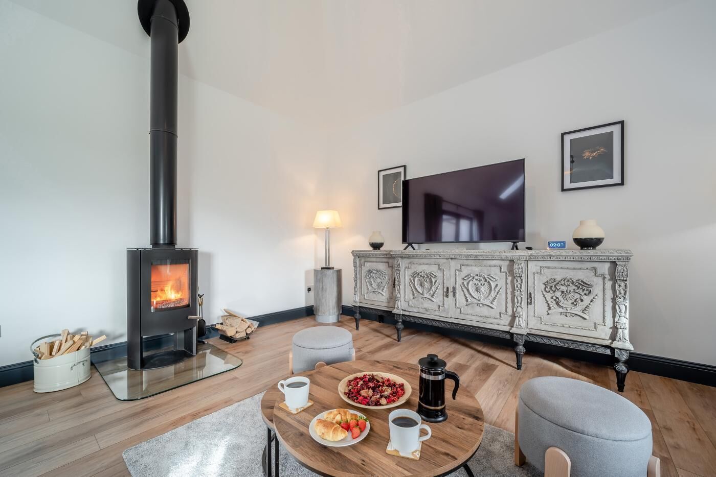 Ein gemütliches Wohnzimmer mit Kaminofen, Fernseher und Essbereich mit gedecktem Frühstückstisch.