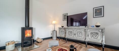 Ein gemütliches Wohnzimmer mit Kaminofen, Fernseher und Essbereich mit gedecktem Frühstückstisch.
