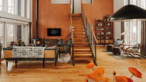 Un salon moderne avec une cheminée, un canapé, une bibliothèque et un escalier.