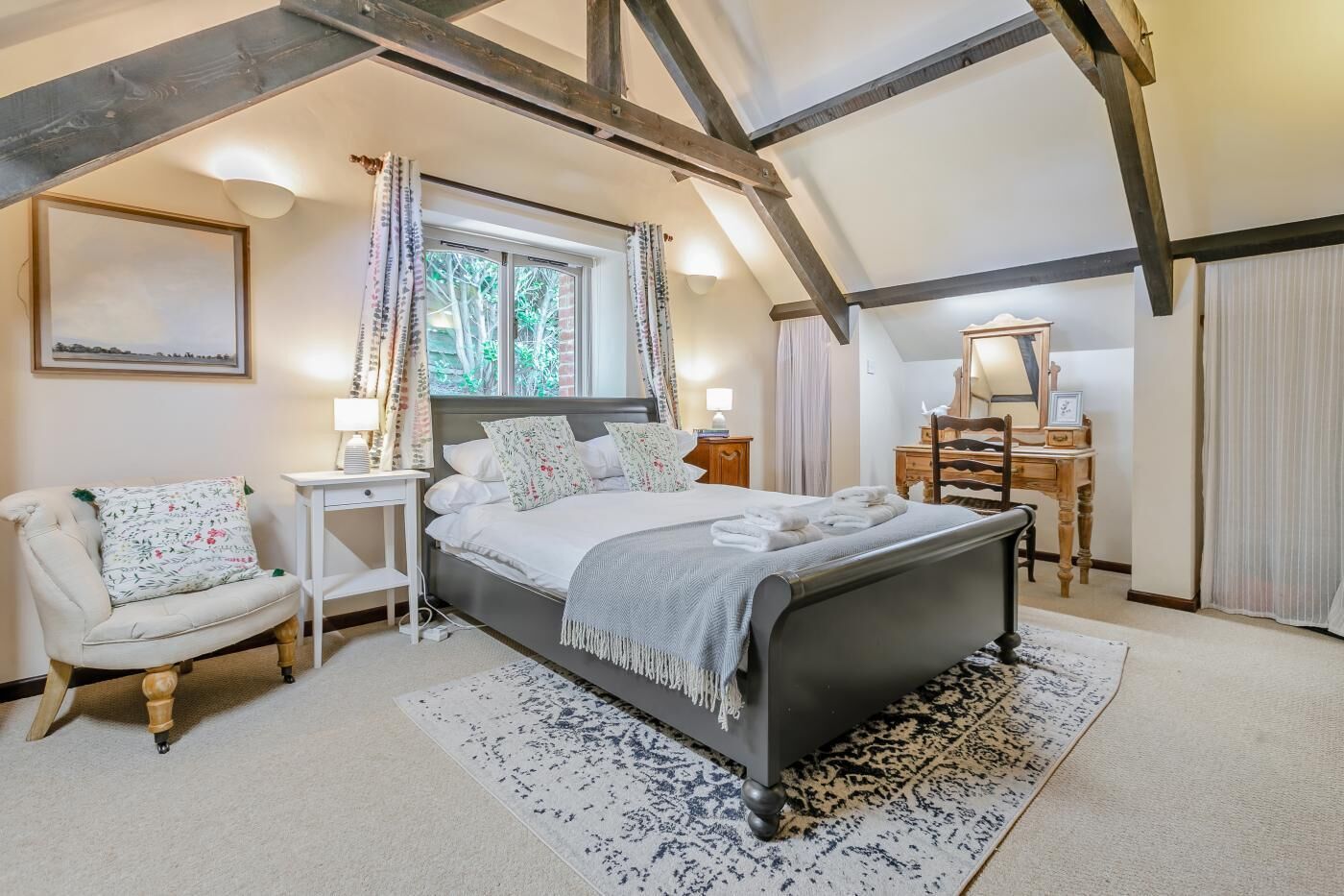 Une chambre à coucher avec un grand lit, une chaise, un bureau et un miroir.