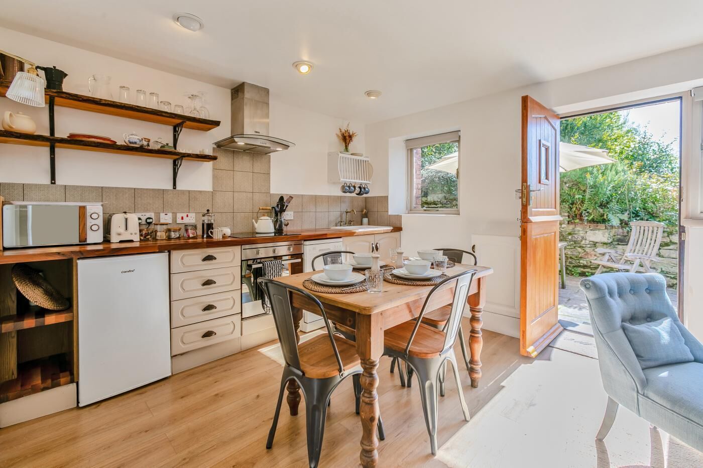 A modern kitchen with wooden cabinets, a built-in microwave, and a dining area with a wooden table and chairs.