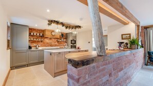 A modern kitchen with a central island, brick walls, and wooden beams. - 4 Bed in Moccas (oc-r33126) (Moccas)