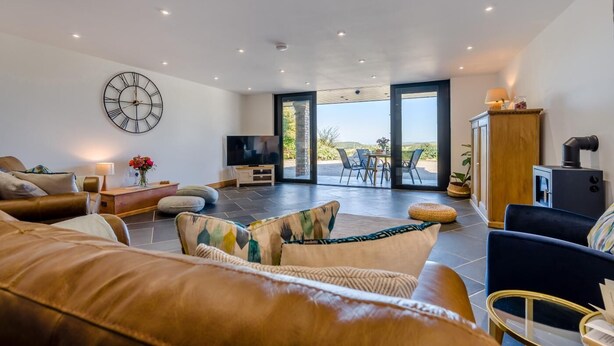 A spacious living room with a large TV, comfortable seating, and a view of the outdoors.