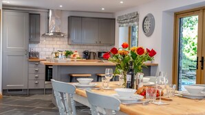 A modern kitchen with grey cabinets, a wooden countertop, and a dining area with white chairs.