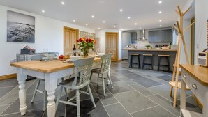 A modern kitchen with a central island, bar stools, and a dining table set for four.