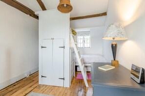 Een slaapkamer met een stapelbed, een bureau met lamp en een kledingkast.