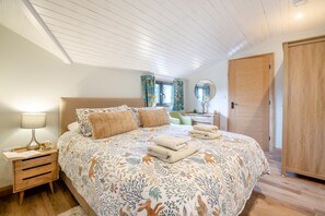A bedroom with a large bed, a nightstand, a dresser, a mirror, and a wardrobe. - 2 Bed in Aberdaron (oc-o33727) (Aberdaron)