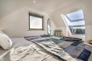 Un dormitorio con una cama grande, una ventana, un espejo y vistas al exterior.