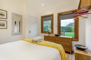 A bedroom with a bed, a dresser, a mirror, and a window with a view of greenery. - 1 Bed in Inverness (oc-a33726) (Inverness)