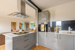 Eine moderne Küche mit Kochinsel, Einbauofen und großem Fenster.
