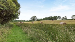 A rural landscape with hay bales and a grassy path. - 4 Bed in Shebbear (oc-a33728) (Shebbear)
