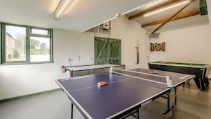 Ein Raum mit Pongtischen, einer Dartscheibe und einem Billardtisch.