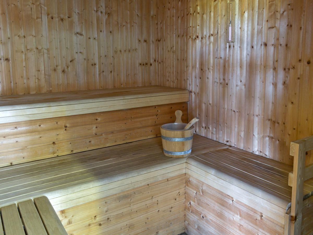 En træsauna med bænke og en træspand.