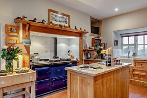Une cuisine avec des meubles en bois, un îlot central et une cuisinière.