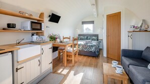 Habitació compacta i ben il·luminada amb cuina americana, zona de menjador i llit.