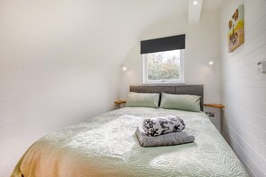 Une chambre à coucher avec un lit, une fenêtre et une œuvre d’art accrochée au mur.