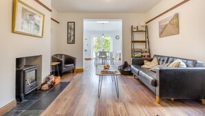 A living room with a fireplace, a sofa, a coffee table, and a dining area with chairs. - 4 Bed in Sheringham (oc-b34006) (Sheringham)