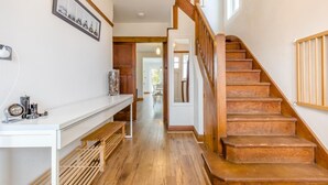 A staircase with wooden steps and a handrail, a white console table with a clock and decorative items, and a framed picture on the wall. - 4 Bed in Sheringham (oc-b34006) (Sheringham)