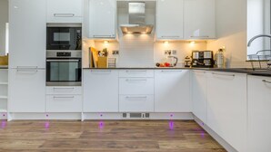 A modern kitchen with white cabinetry, a built-in oven, and a coffee maker. - 4 Bed in Sheringham (oc-b34006) (Sheringham)