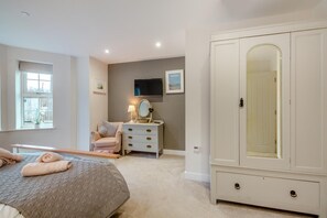A bedroom with a bed, a dresser, a vanity with a mirror, and a wardrobe. - 2 Bed in Benllech (oc-t34071) (Benllech)