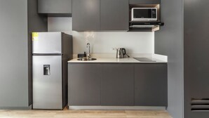 Uma cozinha moderna com frigorífico embutido, micro-ondas, chaleira e lava-loiça.