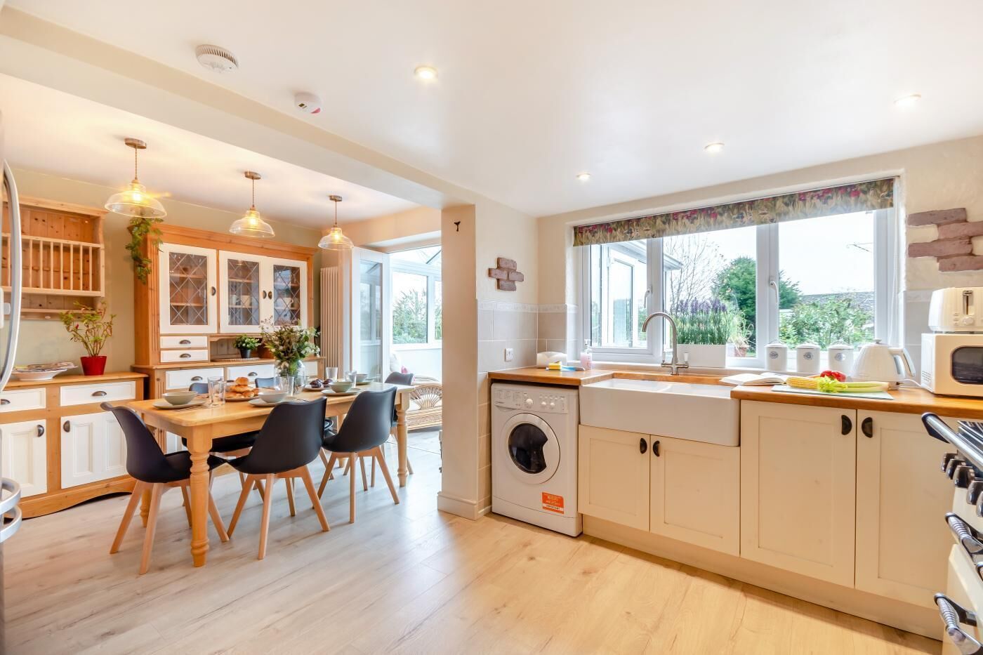 A modern kitchen with wooden cabinets, a built-in dishwasher, and a dining area with a table and chairs.