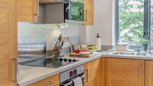 Une cuisine moderne avec des meubles en bois, une cuisinière en acier inoxydable et une fenêtre donnant sur la verdure environnante.