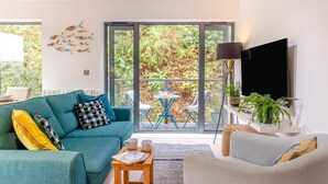 Un salon moderne avec un canapé de couleur turquoise, une table basse et un téléviseur posé sur un meuble.