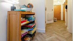 Un couloir avec une bibliothèque en bois remplie de jeux de société et un globe terrestre.