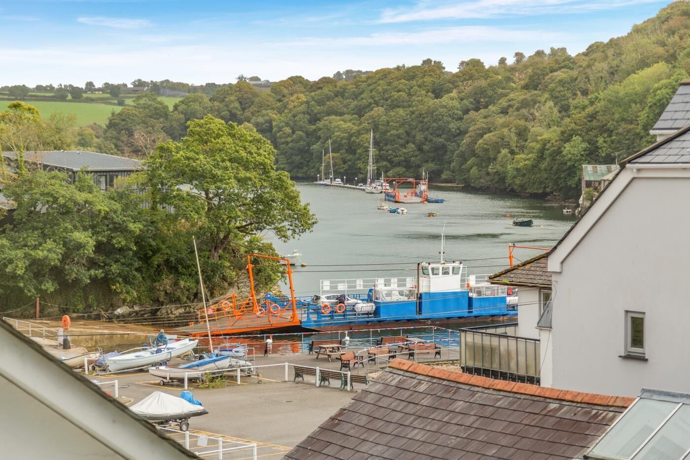 A marina with boats docked, a crane, and a building with a sloped roof.