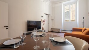 A dining area with a table set for four, a television, and a sofa. - Vigna Nuova District Apartment (Firenze)