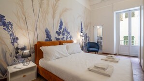 A bedroom with a large bed, a nightstand with a lamp, a chair, and a bathroom visible through an open door. - Vigna Nuova District Apartment (Firenze)