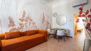 A living room with a sofa, dining table, chairs, and a wall with floral wallpaper. - Vigna Nuova District Apartment (Firenze)
