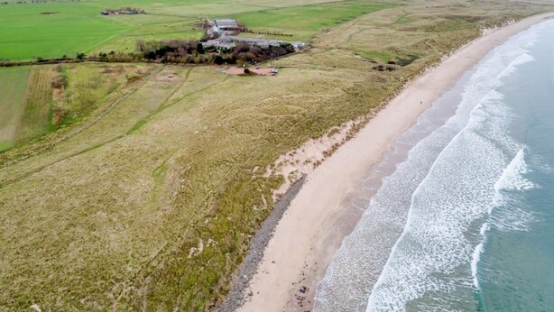 A coastal landscape with a beach, fields, and a building complex. - 2 Bed in Alnwick (oc-80497) (Newton-by-the-Sea)