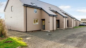 A two-story building with a sloped roof, multiple windows, and a gravel driveway. - 2 Bed in Alnwick (oc-80497) (Newton-by-the-Sea)