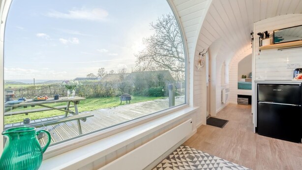 Een moderne keuken met een groot raam, een eethoek met tafel en stoelen, en uitzicht op het landschap.