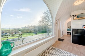 A modern kitchen with a large window, a dining area with a table and chairs, and a view of the countryside.
