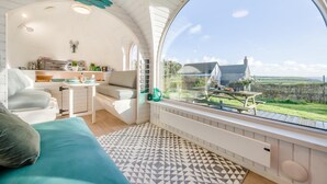 Een gezellig interieur met een groot raam, een bed, een eethoek en een keuken.